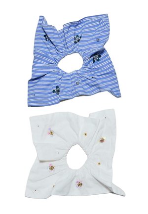 Deux chouchous en tissu, un bleu avec des rayures blanches et des détails floraux foncés, un blanc avec des embellissements floraux violets clairs et jaunes.