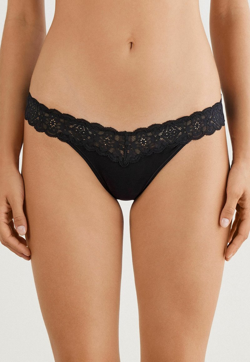 Sorte tanga undertøj med en delikat blondekant, blomster mønstre og glat stof med et minimalistisk design.