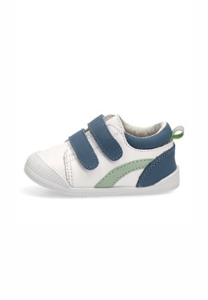 Zapato blanco para bebé con correas de velcro azules, detalles en azul y verde, y una lengüeta para tirar en el talón, mostrado de perfil sobre un fondo blanco.