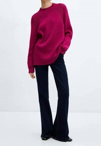 Magenta knit sweater with ribbed neckline and cuffs, paired with dark flared jeans, featuring a smooth texture and relaxed fit.
