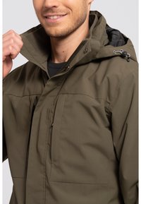 Olive green waterproof jacket with a zip front, high collar, and adjustable hood. Features two front pockets and a smooth texture.