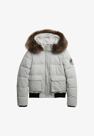 Lichtgrijze pufferjack met een met bont afgewerkte capuchon, voorzien van twee zijzakken en geribbelde manchetten voor een fijne pasvorm.