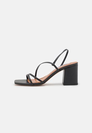 Sorte hælede sandaler med firkantet tå, der har tynde stropper og en chunky blokhæl. Glat tekstur med en naturlig lædersål.