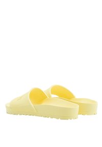 Chanclas amarillas con una parte superior texturizada y una plantilla suave, presentan un diseño de parte trasera abierta y una suela resistente con estrías para un mejor agarre.