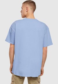 Lys blå oversized bomulls t-skjorte med korte ermer, rund hals og glatt tekstur. Bakdelen er enkel og sømløs.
