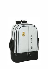 Zaino bianco e nero con texture in rete, doppi scomparti con zip e logo del Real Madrid. Presenta spallacci imbottiti e tasca laterale.