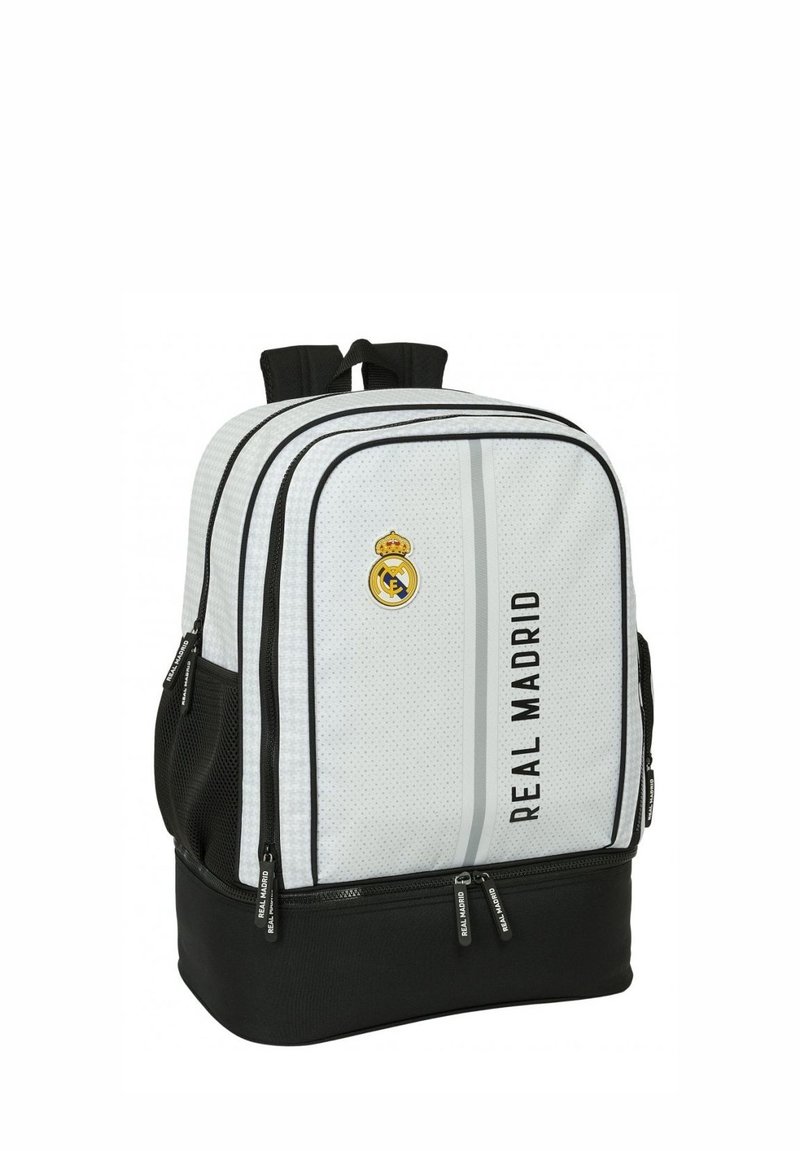 Zaino bianco e nero con texture in rete, doppi scomparti con zip e logo del Real Madrid. Presenta spallacci imbottiti e tasca laterale.