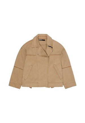 Chaqueta de algodón color camel con cuello ancho, costuras frontales asimétricas, dos bolsillos laterales y detalles de costuras visibles.