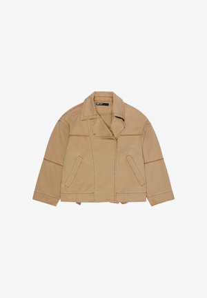 Chaqueta de algodón color camel con cuello ancho, costuras frontales asimétricas, dos bolsillos laterales y detalles de costuras visibles.