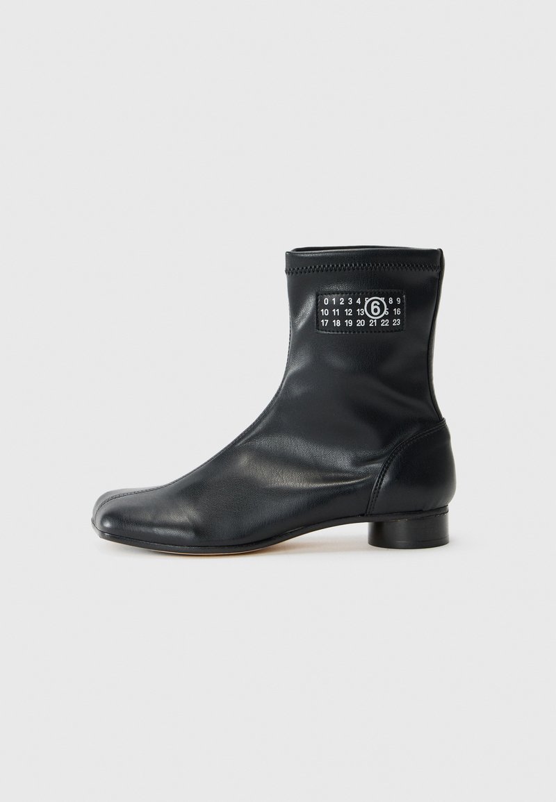 Czarny skórzany botek za kostkę z zaokrąglonym noskiem, niskim słupkowym obcasem, elastycznym otwarciem oraz charakterystycznym białym nadrukiem numerycznym z boku.