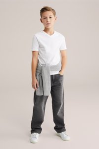 Balti medvilninė marškinėliai, pilkas mezgimo megztinis surištas ties liemeniu, tamsiai pilkos džinsai ir balti sportbačiai. Paprastas dizainas, laisvas stilius ir neutralių spalvų.