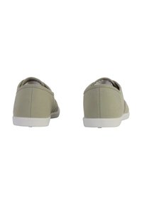 Zapatillas de lona tipo slip-on en verde pálido, con puntera redondeada, suelas blancas y detalles de costura mínimos en la parte trasera.