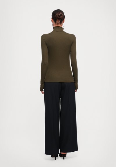 Olive green turtleneck top with long sleeves paired with wide-leg black pants, featuring a textured fabric and a simple design.