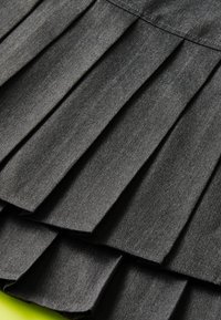 Tissu noir plissé mettant en valeur un design en couches avec une texture lisse. Chaque pli est espacé uniformément et se fond de manière transparente.