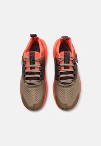 Atletski superge v rjavi, oranžni in zeleni barvni shemi; mrežasti in sintetični materiali; perforirani vzorci; ravni vezalke.