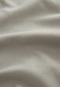 Tela gris claro con una textura suave y un patrón de acanalado fino, cayendo suavemente con un sutil brillo. Sin hardware o acentos visibles.