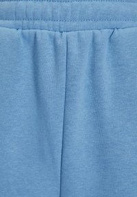 Lichtblauwe zachte stof met elastische tailleband en centrale naaddetail, die wijst op casual broeken of shorts.
