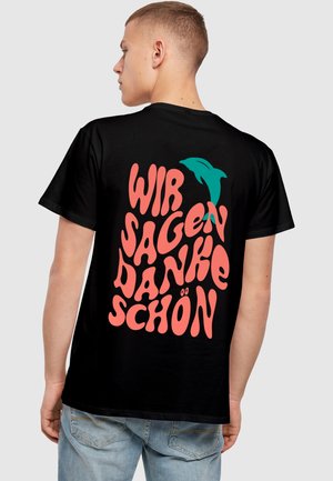 Sort T-shirt med fed, farverig tekst, der står "WIR SAGEN DANKE SCHÖN" samt en turkis delfin grafik, udstyret med korte ærmer.