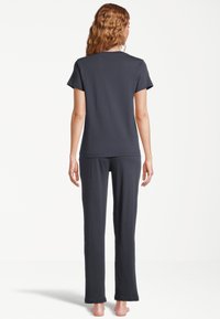 Mörkgrå bomullspyjamas set som består av en kortärmad topp och långbyxor med en avslappnad passform, synlig sömnad och mjuk textur.