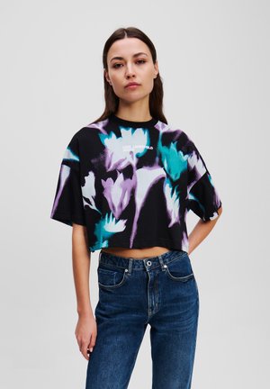 Cropped black t-shirt with a floral pattern in turquoise and purple. Features a round neckline and short sleeves, labeled "KARL LAGERFELD JEANS."
