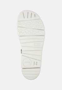 White rubber shoe sole with textured patterns, including grooves and waves. Features a circular logo and size marking "38."