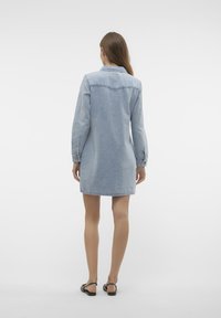 Gai zilu denim kleita ar garām piedurknēm, pogu aizdari, sānu kabatām un brīvu piegriezumu. Priekšējās un aizmugurējās krūšu šuves.