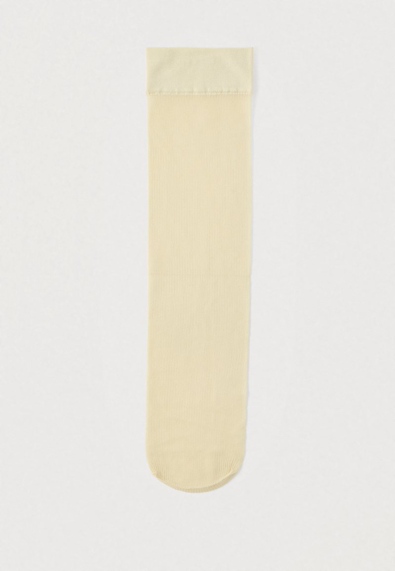 Chaussettes montantes jusqu'aux genoux en beige clair, texture côtelée, finition lisse, bout arrondi et bordure assortie en haut.