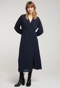 Robe cache-cœur marine à manches longues, avec un décolleté en V profond, des boutons à l'avant et une fente sur le côté ; tissu texturé avec des lignes subtiles.