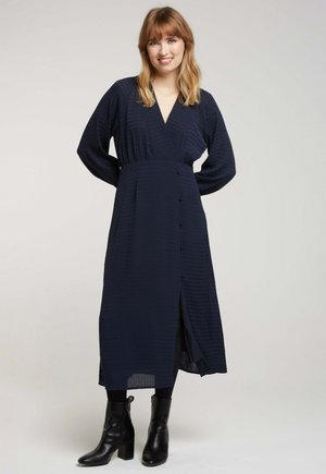 Robe cache-cœur marine à manches longues, avec un décolleté en V profond, des boutons à l'avant et une fente sur le côté ; tissu texturé avec des lignes subtiles.