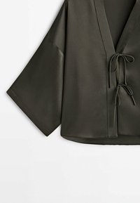Veste style kimono vert olive foncé avec larges manches et deux fermetures par liens devant, présentée sur fond blanc.