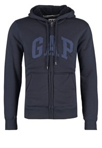 Sweat-shirt bleu marine avec fermeture éclair sur le devant, doté d'un grand logo « GAP », de poignets et d'un ourlet côtelés, et d'une doublure intérieure douce.