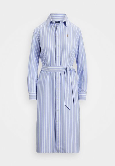 Svetlo modra obleka s poudarjenimi belimi črtami, z gumbi spredaj in pasom. Ima dolge rokave in togo ovratnik.