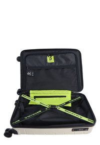 Hartschalenkoffer in Creme mit schwarzer Innenauskleidung. Verfügt über Doppelräder, eine Innentasche aus Mesh, neon grüne Riemen und ein Zahlenschloss.