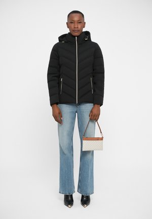 Black puffer jacket with a hood, featuring chevron stitching and front zippers. Paired with light blue flared jeans and a small handbag.