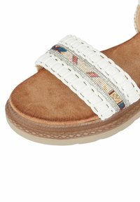 Sandal in tessuto bianco con numerosi intrecci e soletta marrone testurizzata. Presenta una banda ricamata colorata con dettagli metallici e un suola beige flessibile.