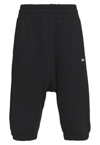 Schwarze cropped Jogginghosen mit elastischem Bund. Weicher Stoff mit lockerer Passform, mit einem kleinen weißen Logo auf der linken Seite.