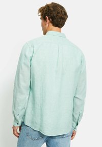Mintgroene, lange mouw blouse van lichtgewicht linnen, met een rugplooien, knoopmanchetten en een gebogen zoom.