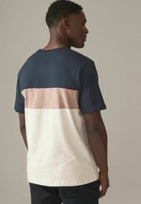 Kortærmet t-shirt med en marineblå overdel, rosefarvet midtersektion og cremet bund, lavet af blød, tekstureret bomuldsstof.