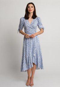 Jasnoniebieska sukienka kopertowa w biały kwiatowy wzór, z bufkami i przewiązywanym w talii, z asymetrycznym dołem i miękką teksturą materiału.