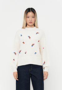 Cremfarbener, kurz geschnittener Pullover mit Rundhalsausschnitt aus gestricktem Material und buntem floralen Stickdesign. Mit gerippten Bündchen und unterem Saum. Lockerer Schnitt.