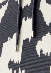 Tela a rayas en blanco y negro con una superficie texturizada; cuenta con dos cordones oscuros con aglets plateados.