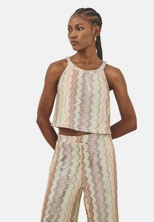 Top corto de lentejuelas con cuello halter en colores pastel. Presenta patrones en zigzag y un corte holgado. Combinado con pantalones de lentejuelas a juego.