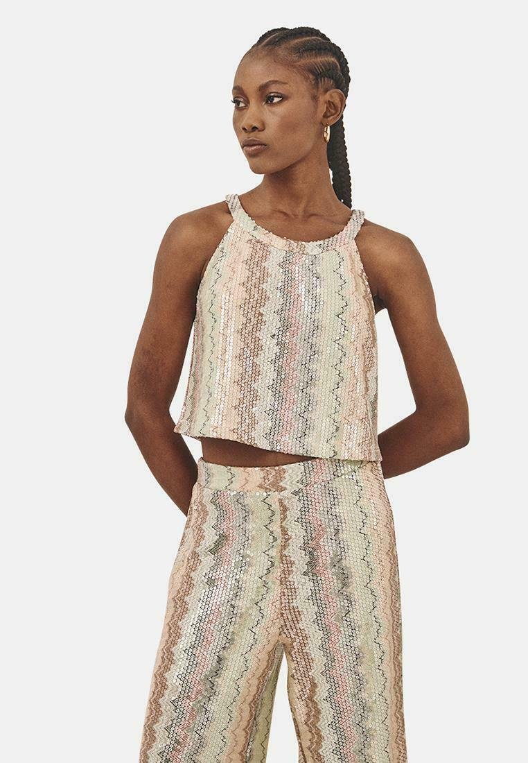 Top corto de lentejuelas con cuello halter en colores pastel. Presenta patrones en zigzag y un corte holgado. Combinado con pantalones de lentejuelas a juego.