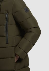 Zelena napihljena jakna z gladko, mat teksturo. Ima žep na zadrgo na prsih in logotip na levem rokavu.