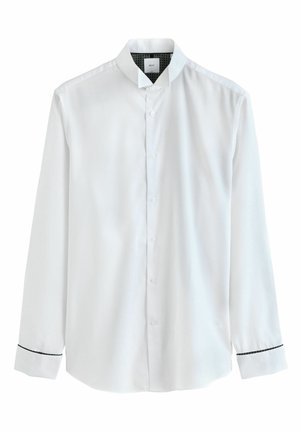 Balta garām piedurknēm kreklā ar pogu aizdari, stāvošo apkakli un melnu akcentu uz rokturēm. Gluda auduma ar maigu tekstūru.