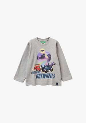 Grijze longsleeve shirt met een cartoonontwerp van auto's en een motorfiets, tegen een stedelijke skyline, met de tekst "CALLING ALL BATWHEELS".