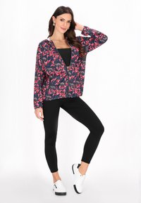 Blomstret zip-up jakke i marineblå, med røde og pink mønstre. Sammen med sorte leggings og hvide sneakers. Glat stof med en afslappet pasform.