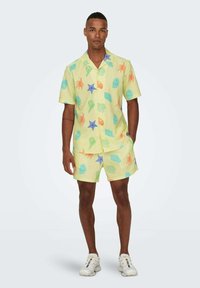 Camisa de manga corta amarilla y pantalones cortos a juego con patrones coloridos inspirados en el mar. Fabricados con un tejido ligero y un acabado texturizado.