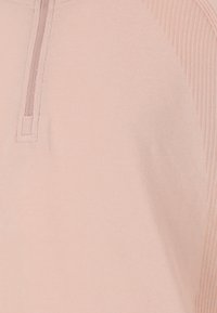 Ljusrosa henley-tröja med en strukturerad ribbad design på ena sidan och en kvartslång dragkedja vid kragen. Mjuk tyg.