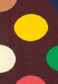 Tela con un fondo marrón y grandes puntos coloridos en amarillo, melocotón, verde y azul. Textura suave con apariencia de tejido de punto.